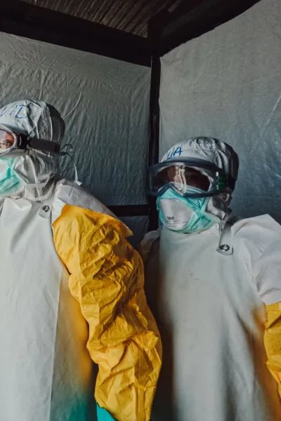 Tre personer i heltäckande eboladräkter står uppradade.