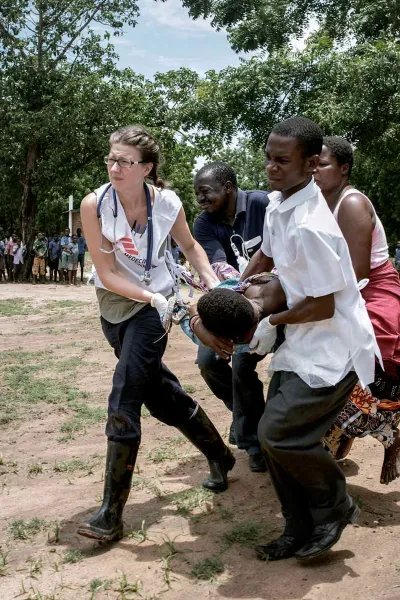 Four medical workers are carrying a patient.