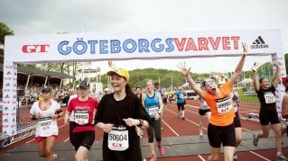 Glada människor som springer över mållinjen inne på en sportarena