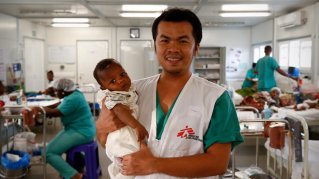 Ett spädbarn i famnen på en sjuksköterska som som står på en mödravårdsavdelning