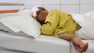 Ett barn som fått vård för en skottskada i huvudet vilar på en sjukhussäng.