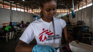 Kvinna i Läkare Utan Gränser t-shirt öppnar ett paket