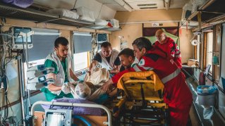 En skadad patient flyttas från ambulansbår till en säng ombord på Läkare Utan Gränsers medicinska tåg