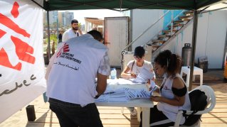 människor i vita västar med läkare utan gränsers logotyp organiserar en tillfällig sjukvårdsklinik på stranden i beirut