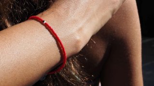 Ett rött armband på en person som håller om en annan.