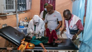 En kvinna och två män hjälper ett barn på en brits på en klinik