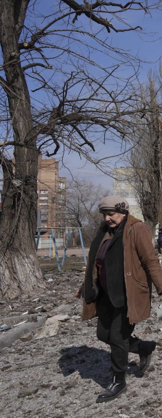 En kvinna går bredvid ett hus som har förstörts av bomber i Mariupol, Ukraina.