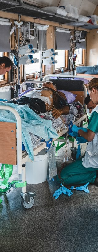 Personal på intensivvårdsavdelningen på Läkare Utan Gränsers tåg övervakar och stabiliserar en svårt krigsskadad patient under en resa från Pokvrosk i östra Ukraina till Lviv i västra Ukraina.