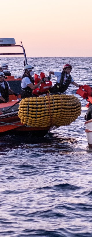 En gummibåt från Läkare Utan Gränsers sök- och räddningsfartyg Geo Barents undsätter en grupp människor från en träbåt på centrala Medelhavet.