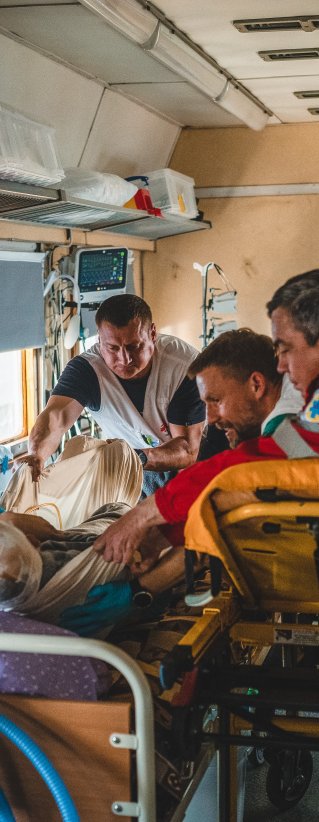 En skadad patient flyttas från ambulansbår till en säng ombord på Läkare Utan Gränsers medicinska tåg