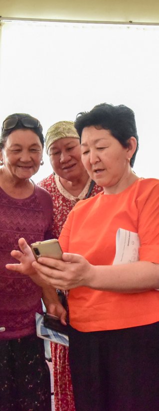 Fem kvinnor står bredvid varandra och kollar på en mobil