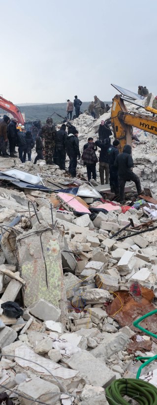 En grävskopa gräver i rasmossorna efter en stora jordbävning som drabbade Turkiet och Syrien.
