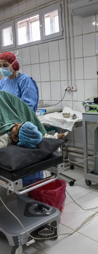 En kvinna ligger på en säng med läkare runt omkring henne