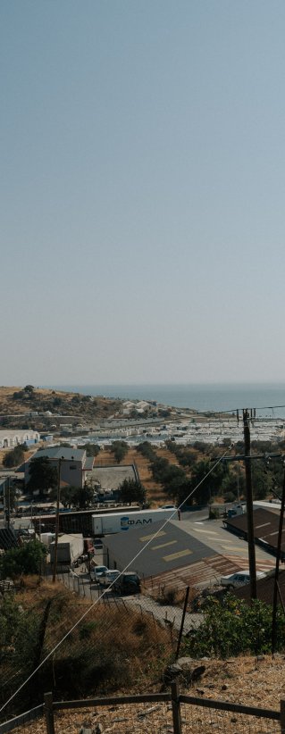 Silutten av en person med keps ses kolla ut över havet framför hen.