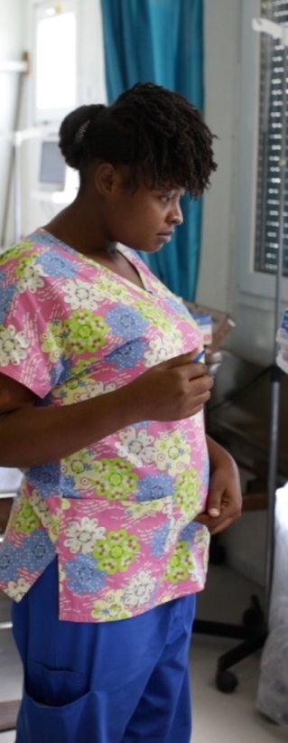 Sjuksköterskan Gessica i Haiti talar med en patient som ligger i en sjukhussäng