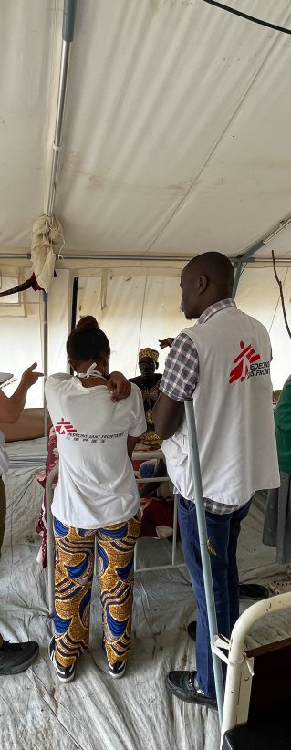 Läkare Utan Gränsers anställda står i ett stort uppbyggt tält med sjukvårdssängar och patienter runt om.