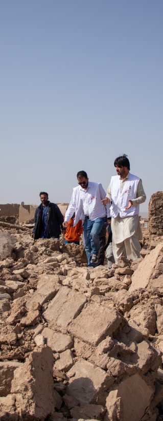 Tre medarbetare från Läkare Utan Gränser går över stora rasmassor efter jordbävningen i Afghanistan