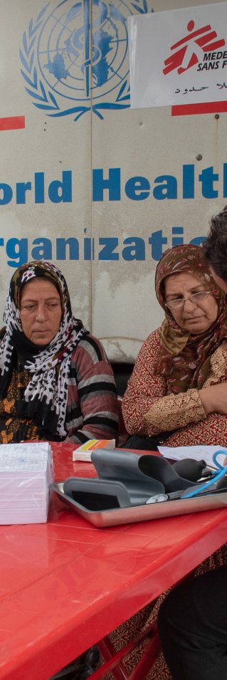 Tre patienter får vård av två läkare framför vår mobila klinik