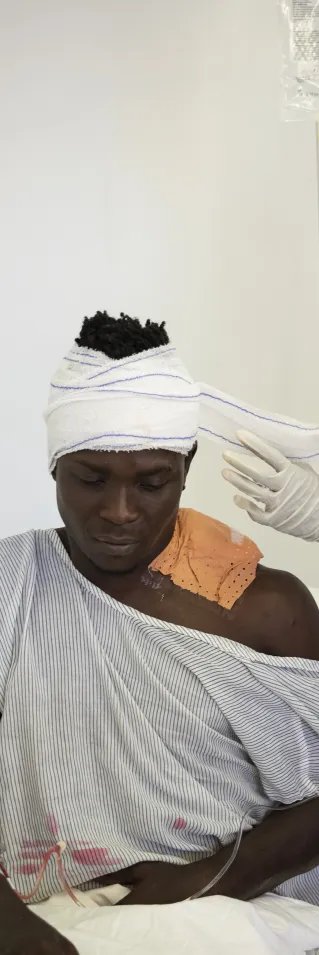 En man med bandage på huvudet tas hand om av medicinsk personal