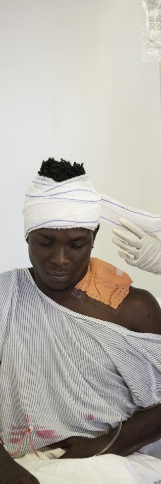 En man med bandage på huvudet tas hand om av medicinsk personal