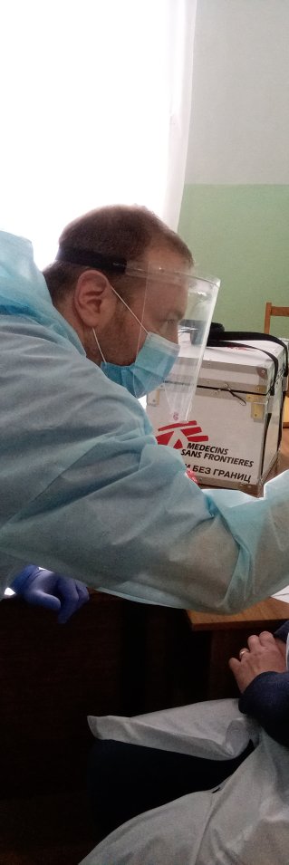 En man tar en halsprov på en sittande kvinna.