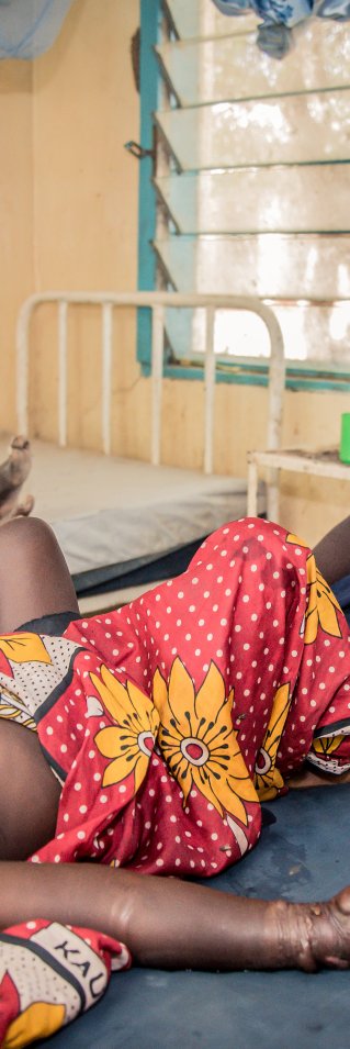 En flicka som blivit ormbiten ligger på en brits på ett sjukhus i Kenya, hennes mamma sitter bredvid och tittar in i kameran. 