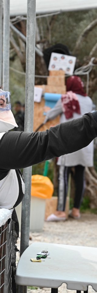 Medicinsk personal tar temperaturen på ett barn i flyktinglägret Moria, på den grekiska ön Lesbos.