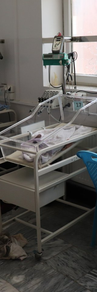 Tomma sängar för nyfödda i en sjukhussal, blod på golvet.