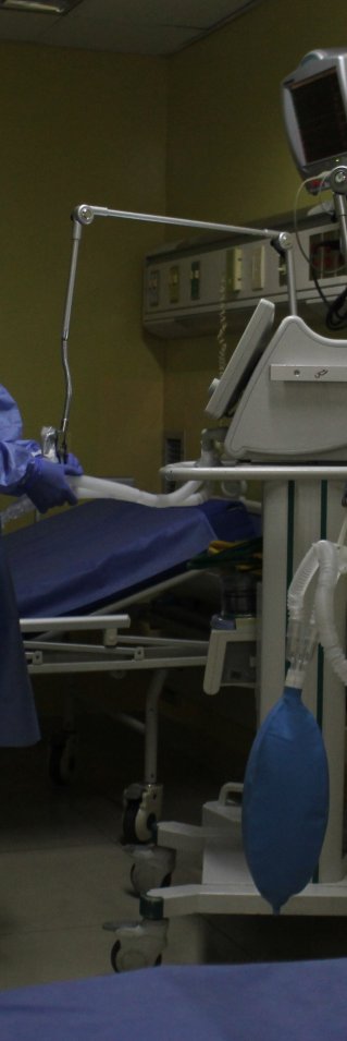 En medicinsk personal står iklädd skyddsutrustning och tittar på en monitor.