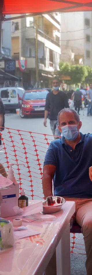 En man sitter på en stol och får vård vid en mobil klinik efter explosionen i Beirut, Libanon.