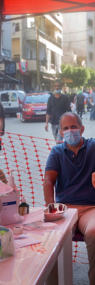 En man sitter på en stol och får vård vid en mobil klinik efter explosionen i Beirut, Libanon.