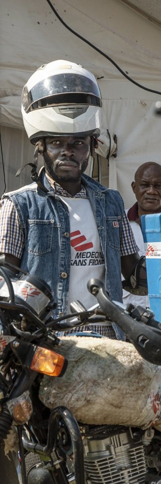 En man står vid en motorcykel vid en vaccinationskampanj mot mässling i Kongo-Kinshasa.
