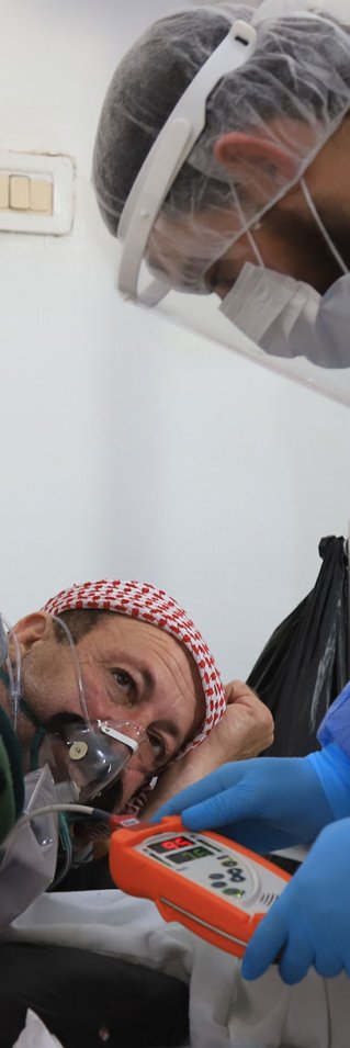 En sjuksköterska tittar till en patient med misstänkt covid-19 på sjukhuset i Idlib, Syrien.