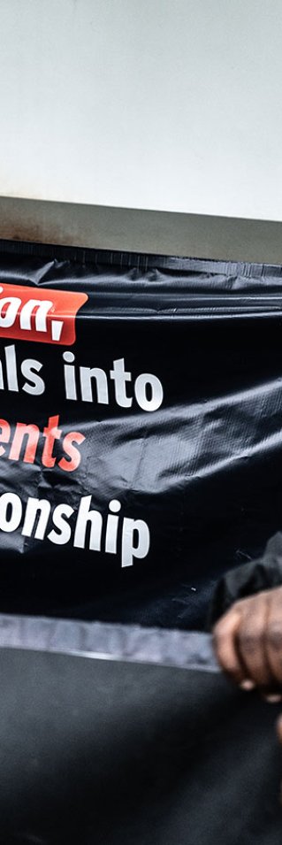 En man står vid ett plakat vid en demonstration för rättvis fördelning av covidvaccin i Sydafrika.