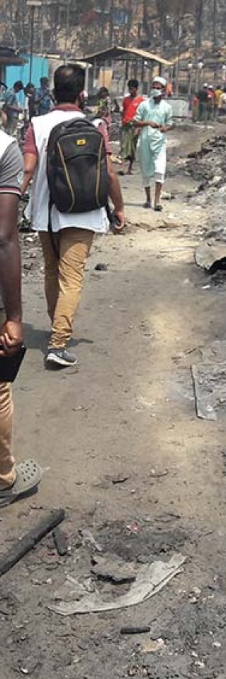 Två personer från Läkare Utan Gränser går genom det nedbrunna lägret i Cox,s Bazar, Bangladesh.