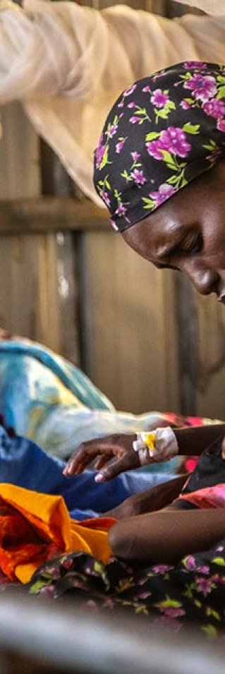 Rauda Adam Isa klappar sin dotter på pannan i en sjukhussäng på sjukhuset El Fasher, norra Darfur, Sudan.