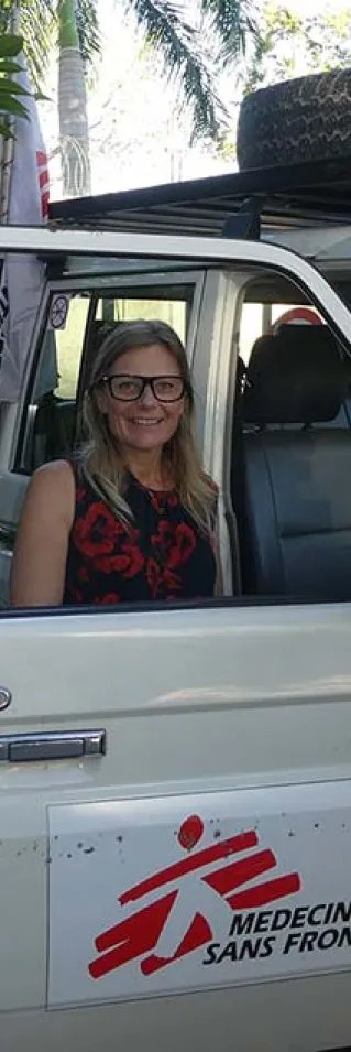 Sjuksköterskan Ulli Hedberg, som är i Haiti, står bakom en bildörr och tittar in i kameran.