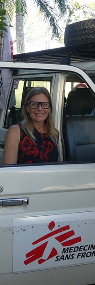 Sjuksköterskan Ulli Hedberg, som är i Haiti, står bakom en bildörr och tittar in i kameran.