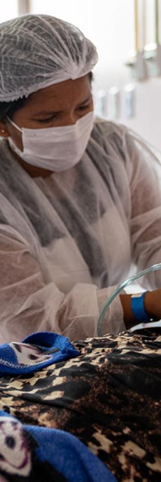 Sjukvårdspersonal hjälper 109-åriga Bonifácia de Oliveira med andningen. Bonifácia ligger i en säng där hon vårdas för covid-19 på ett sjukhus i Brasilien där Läkare Utan Gränser jobbar för att stötta covidinsatsen i Amazonasregionen