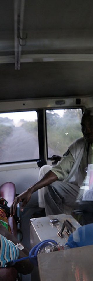 En anställd från Läkare Utan Gränser i Kongo-Kinshasa sitter bredvid en kvinna som ligger på en bår i en ambulans.