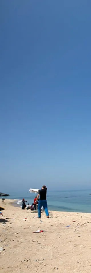 En ung man går på kryckor på en strand i Gaza, Palestina.