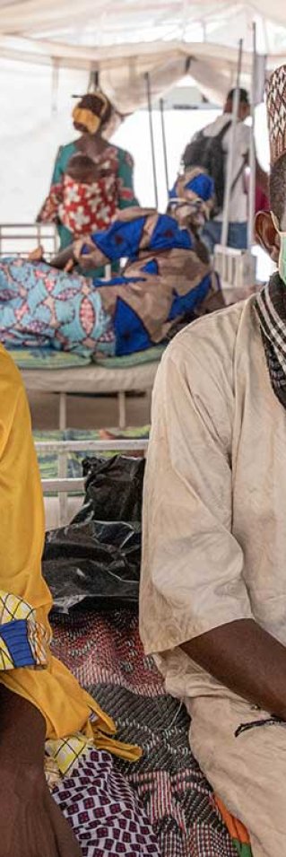 Ali, som vårdas på sjukhuset  i Magaria i Niger för malaria och uttorkning, sitter i sin mammas knä på en säng.