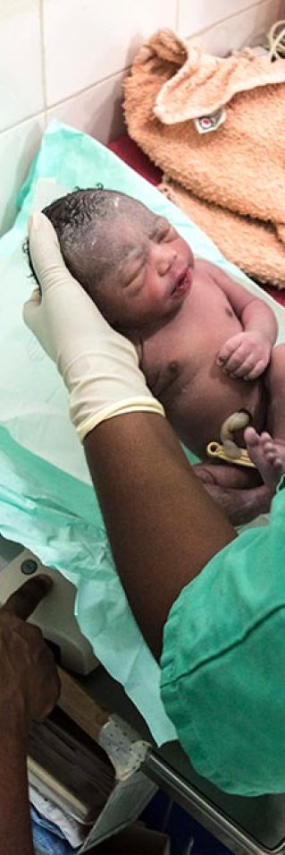 En nyfödd bebis ligger i händerna på sjukvårdspersonal på Läkare Utan Gränsers mödravårds- och förlossningsklinik  i Jahun, norra Nigeria.