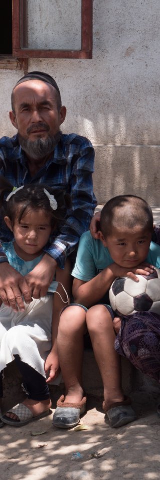 Surayo sitter med sina barn, sina föräldrar och en brorson på trappan framför deras hus i västra Tadzjikistan.