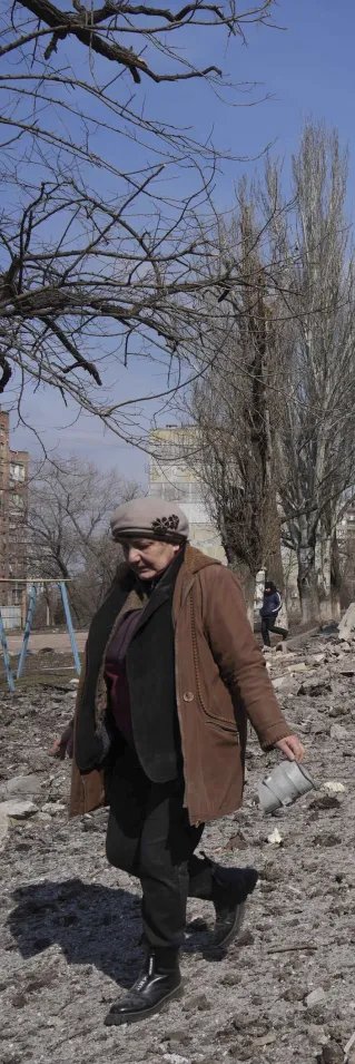 En kvinna går bredvid ett hus som har förstörts av bomber i Mariupol, Ukraina.