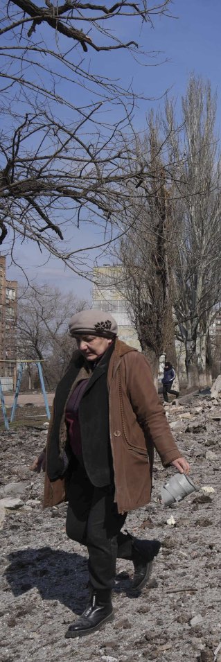 En kvinna går bredvid ett hus som har förstörts av bomber i Mariupol, Ukraina.
