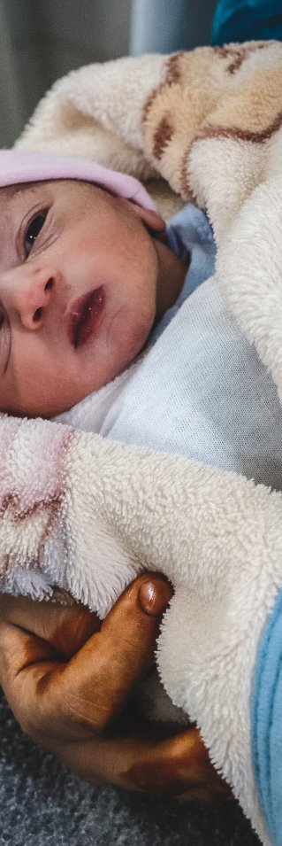 Bebisen Layth ligger på sin mammas arm på mödravårdsmottagningen al-Amal i Mosul, Irak.