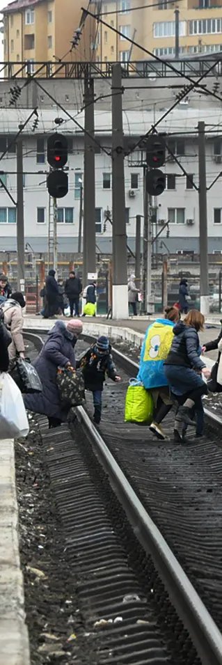 Människor med bagage korsar tågspåren i den ukrainska staden Lviv.