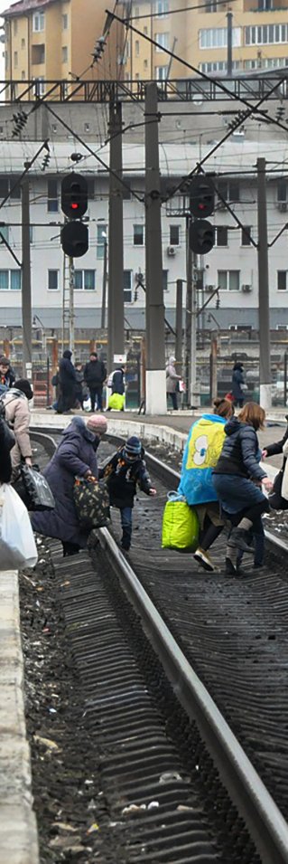 Människor med bagage korsar tågspåren i den ukrainska staden Lviv.