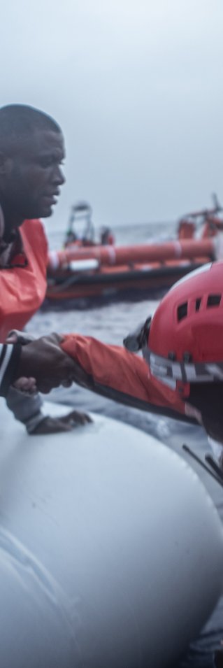 En man får hjälp av Läkare Utan Gränsers medarbetare att ta sig från en vattenfylld gummibåt till vår båt som ingår i vår sök- och räddningsinsats på centrala Medelhavet.